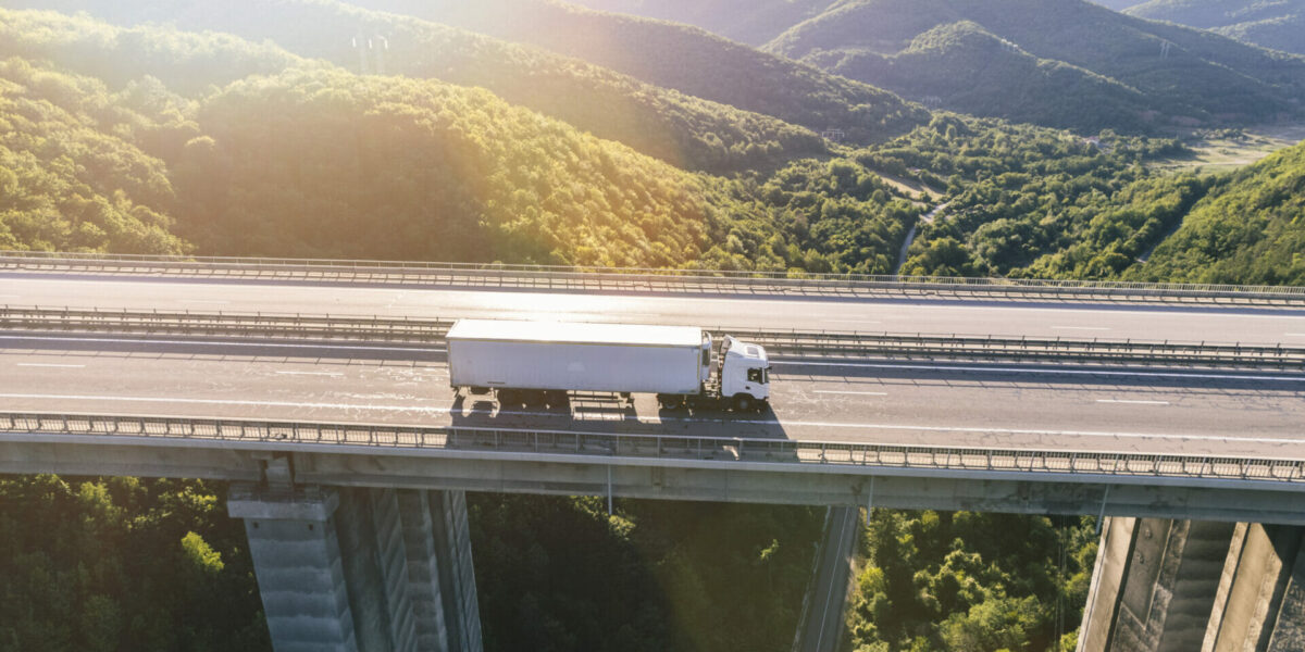 trucks on highway in mountain at sunset aerial view